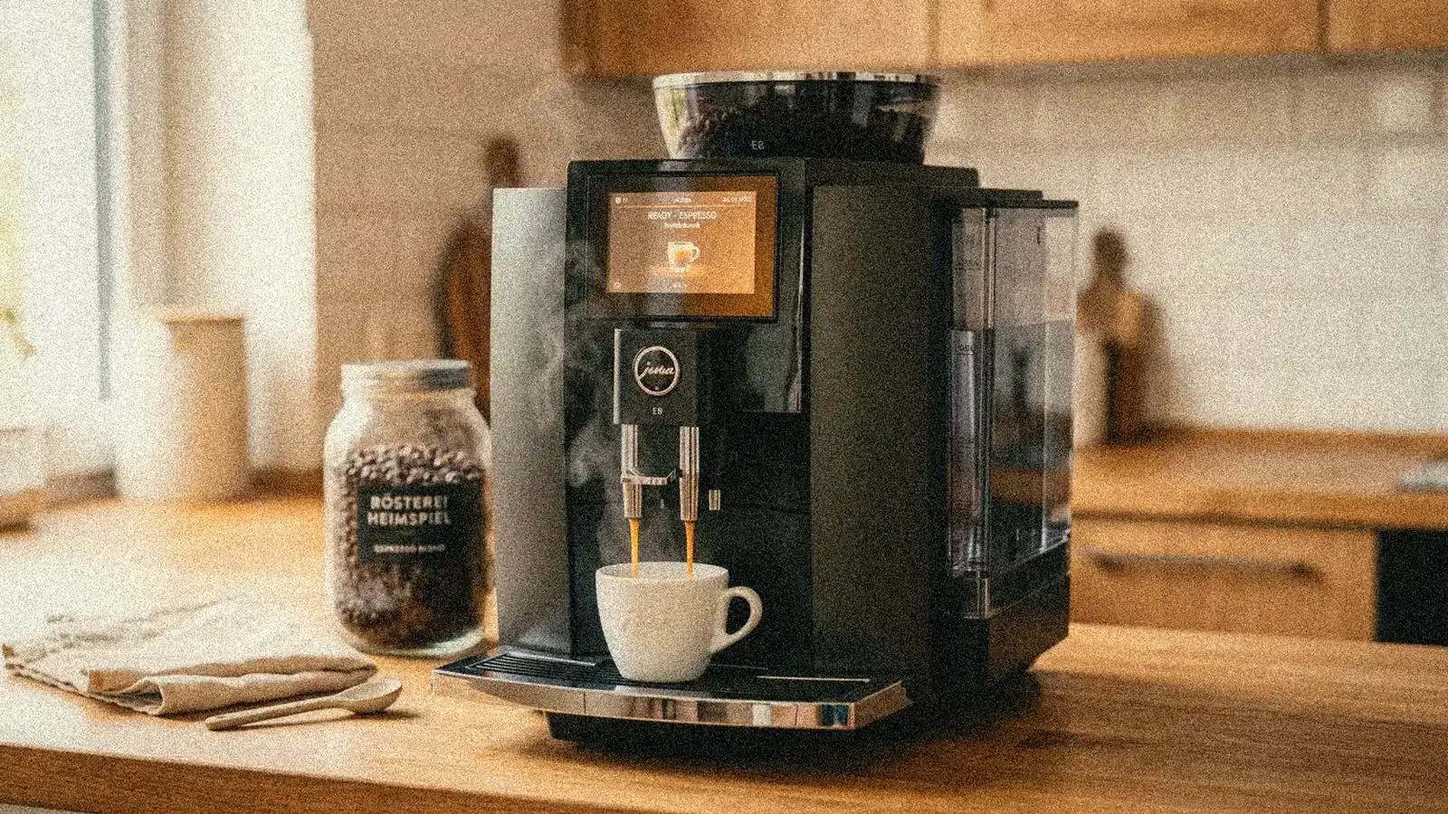 Jura E8 Test in einer hellen Wohnküche: frischer Espresso fließt mit dichter Crema unter dem Doppelauslauf in eine weiße Tasse.